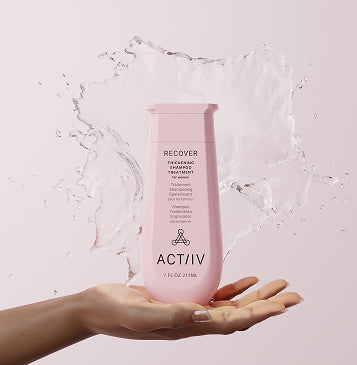 ACTIIV Recover thickening shampoo treatment held in hand with water splash, formulated to cleanse scalp and support the appearance of thicker hair