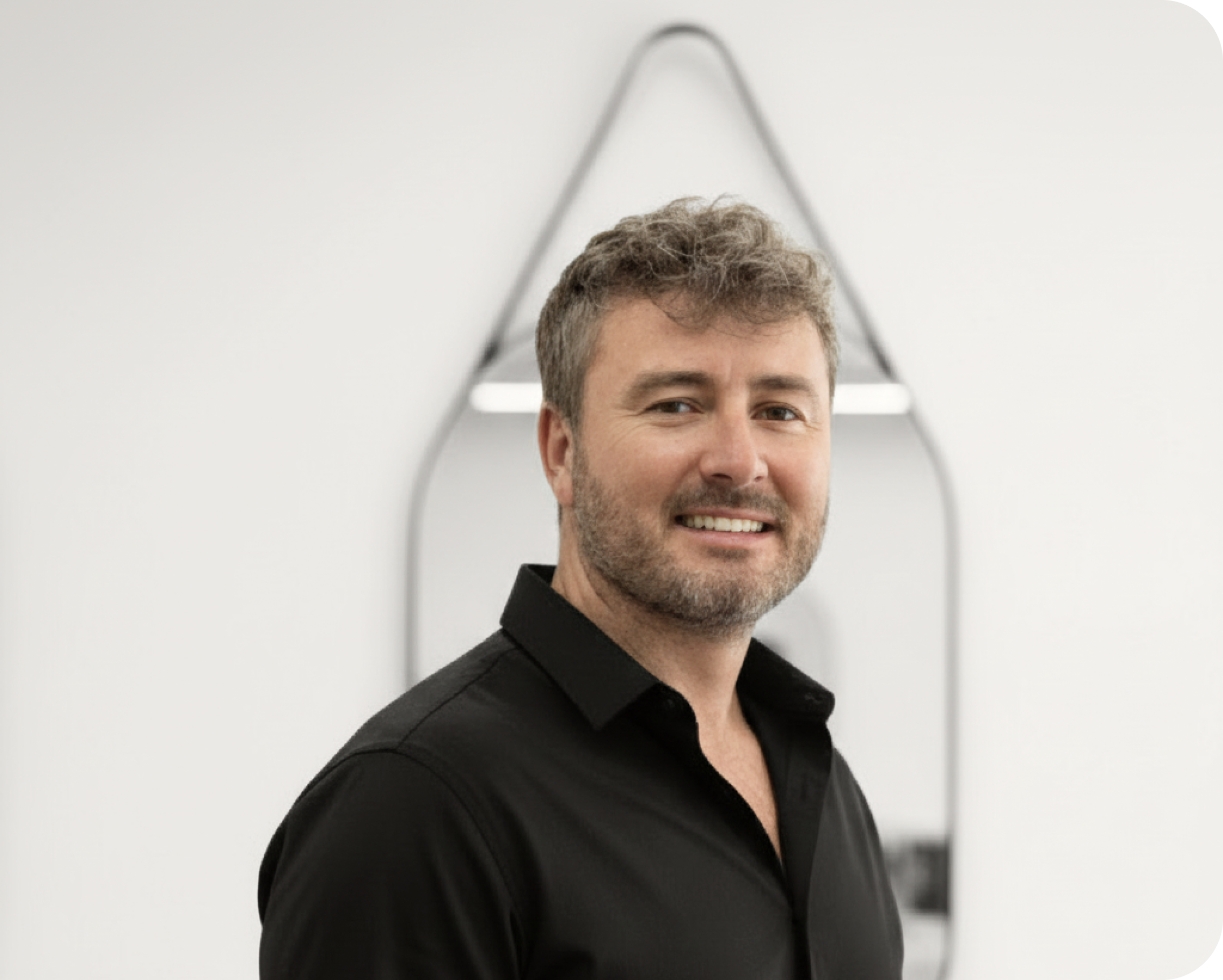 Man wearing a black shirt standing in front of a modern white wall