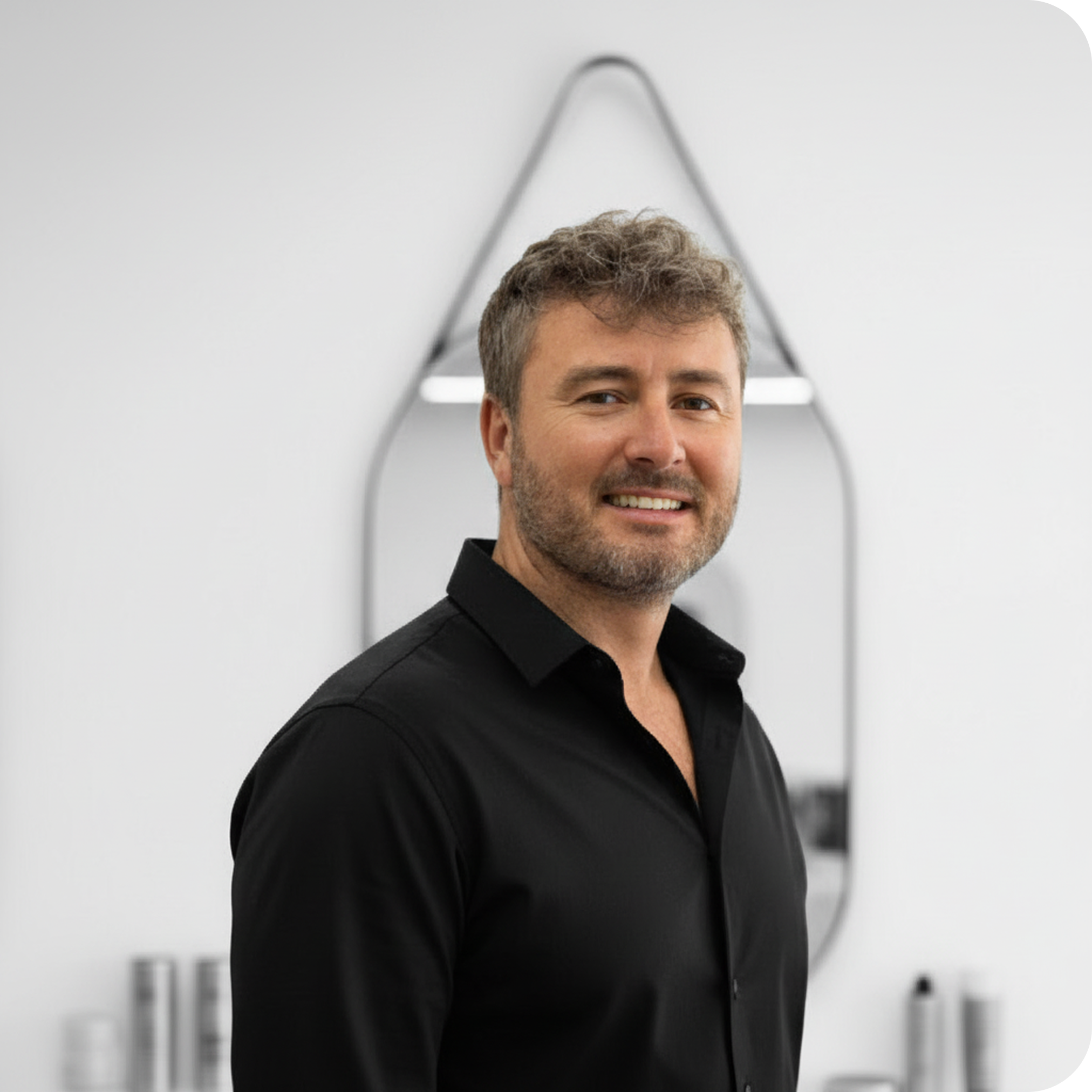 Man in a black shirt standing in front of a modern mirror