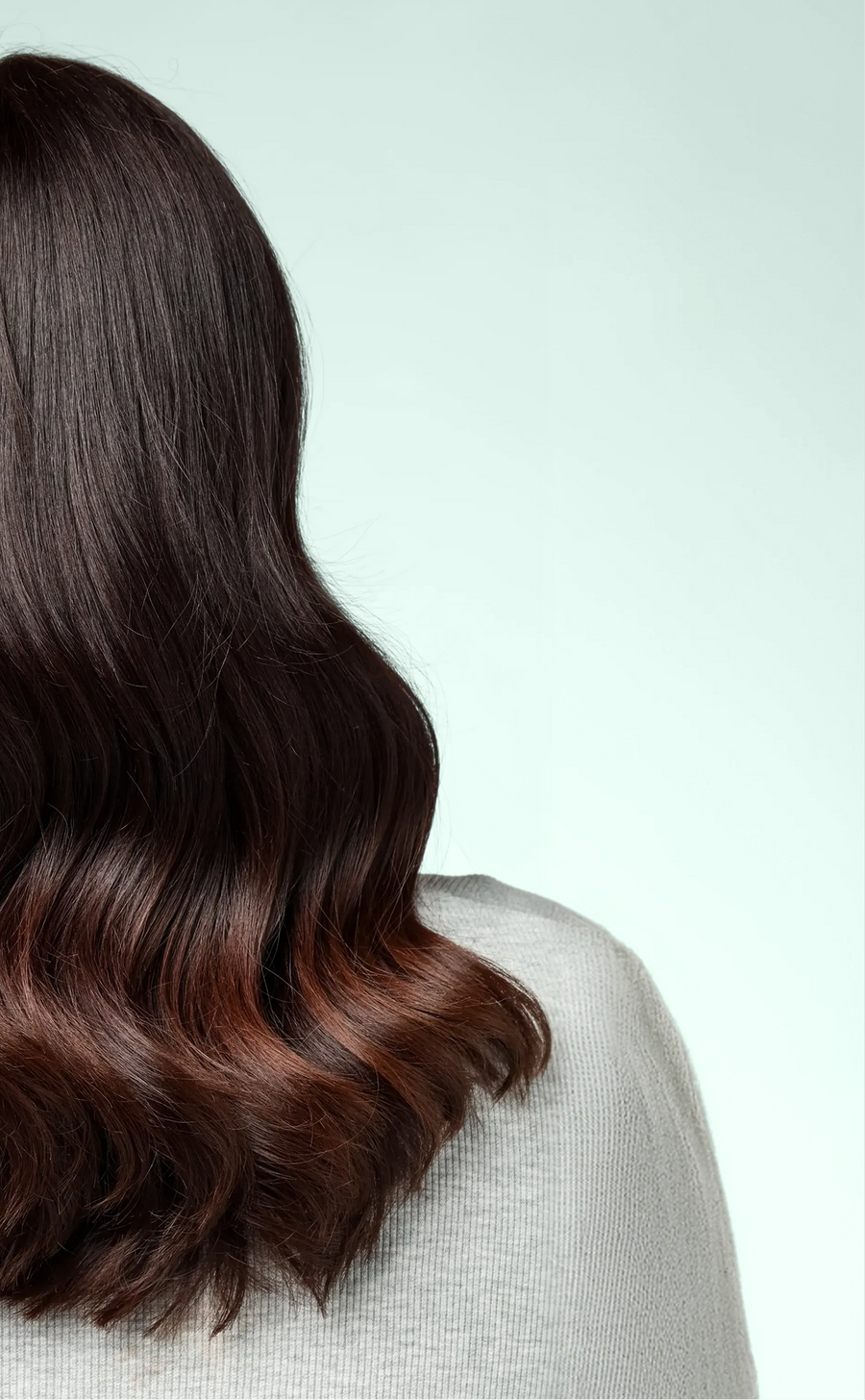 Back view of smooth, glossy brunette hair styled in soft waves after using ACTIIV INTEGRITYrx hair care.