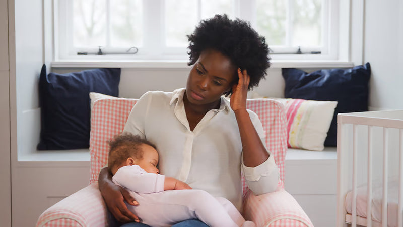 Mother holding her baby while experiencing postpartum hair changes and thinning hair