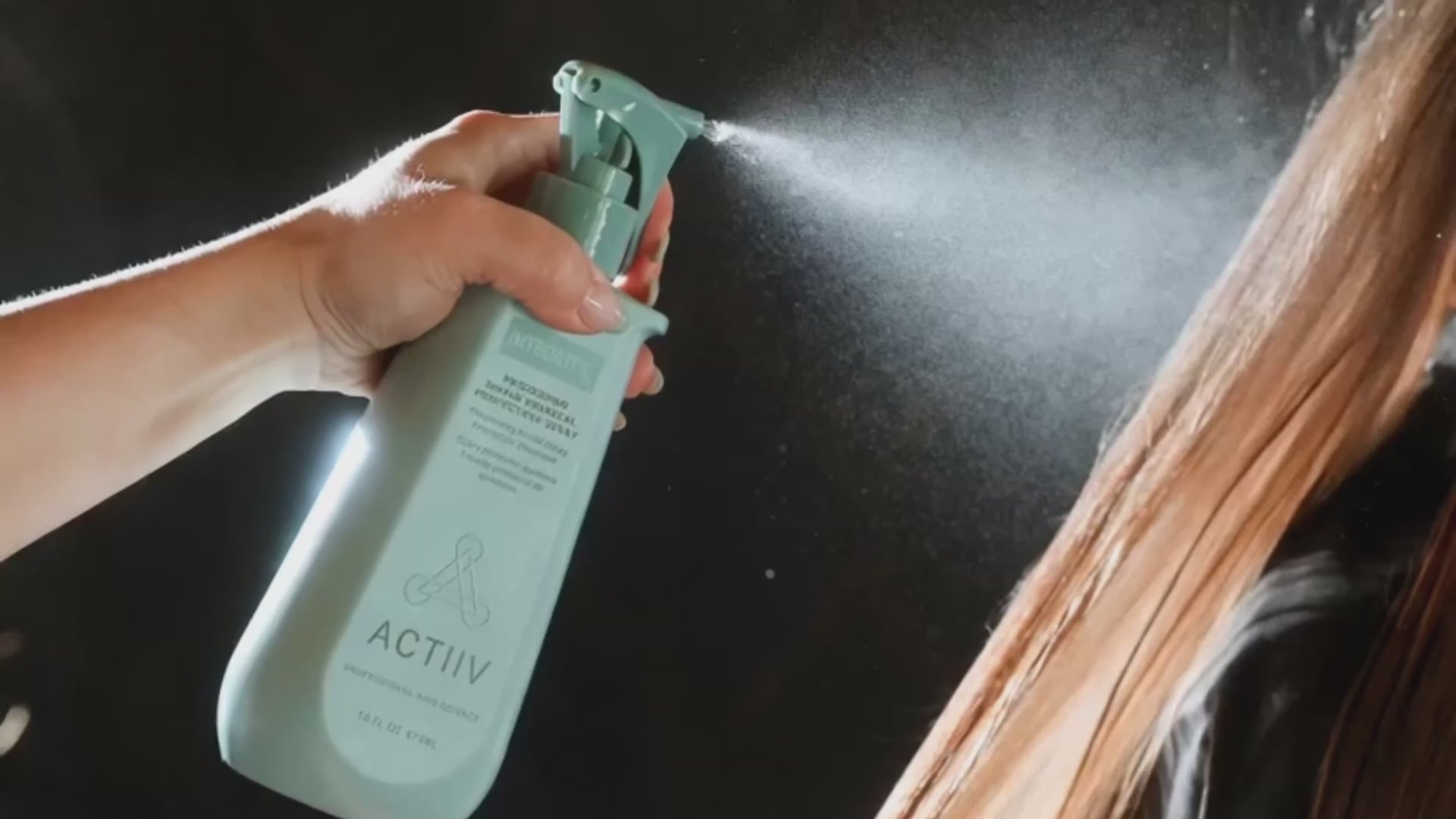 ACTIIV educator spraying product through a model's hair
